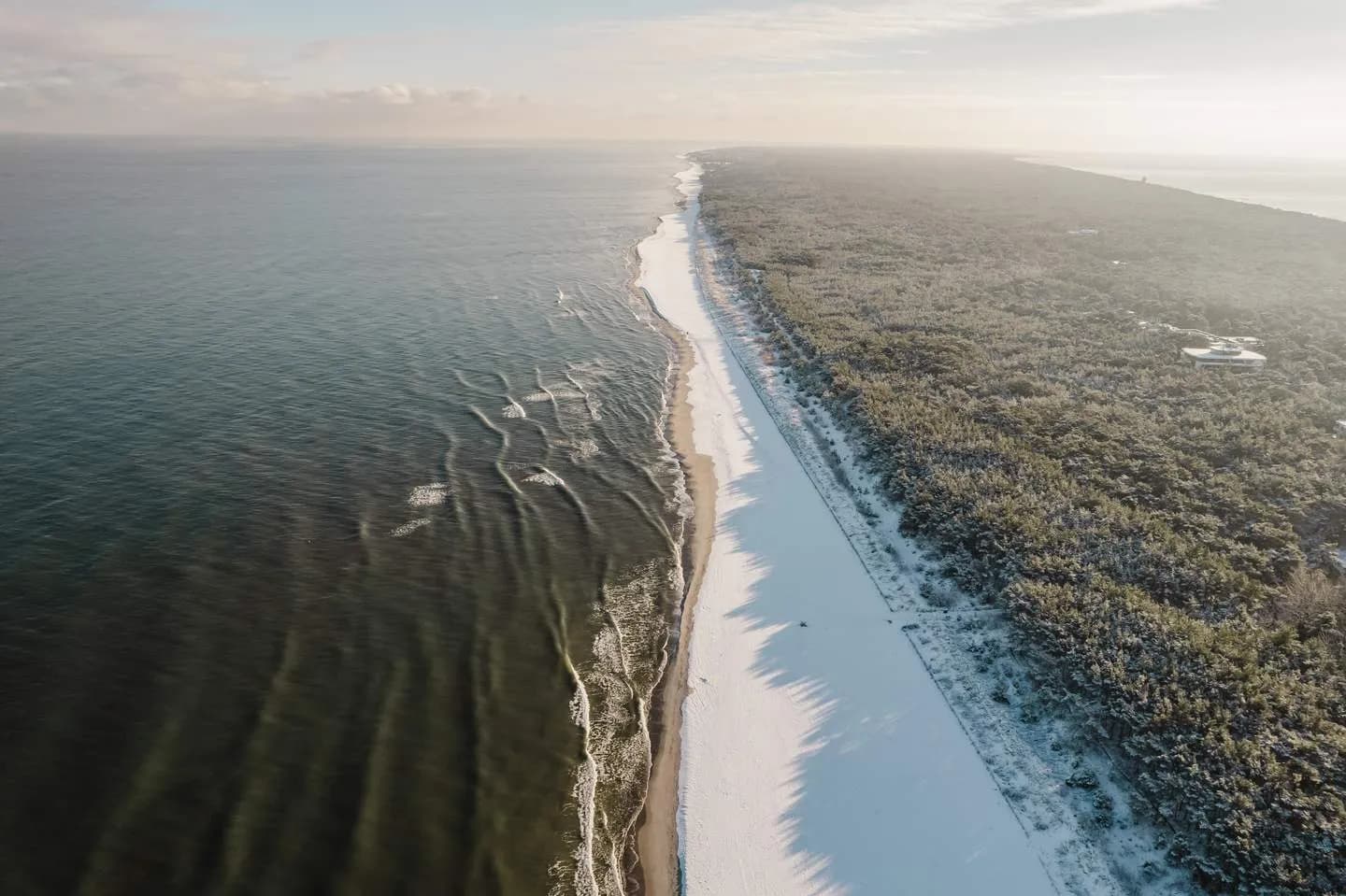 Zaśnieżona plaża i las w Juracie z lotu ptaka
